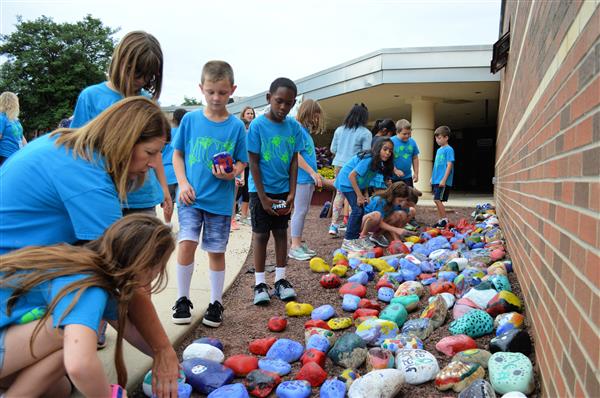 Students carefully arrange their rocks alongside the front entrance to the building. 